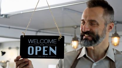 A small business owner puts up an Open sign.